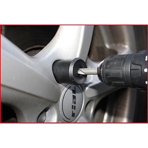 Ein Bohrer entfernt eine Radmutter von einer silbernen Felge. Das Wort "Rial" ist auf der Felge zu sehen.